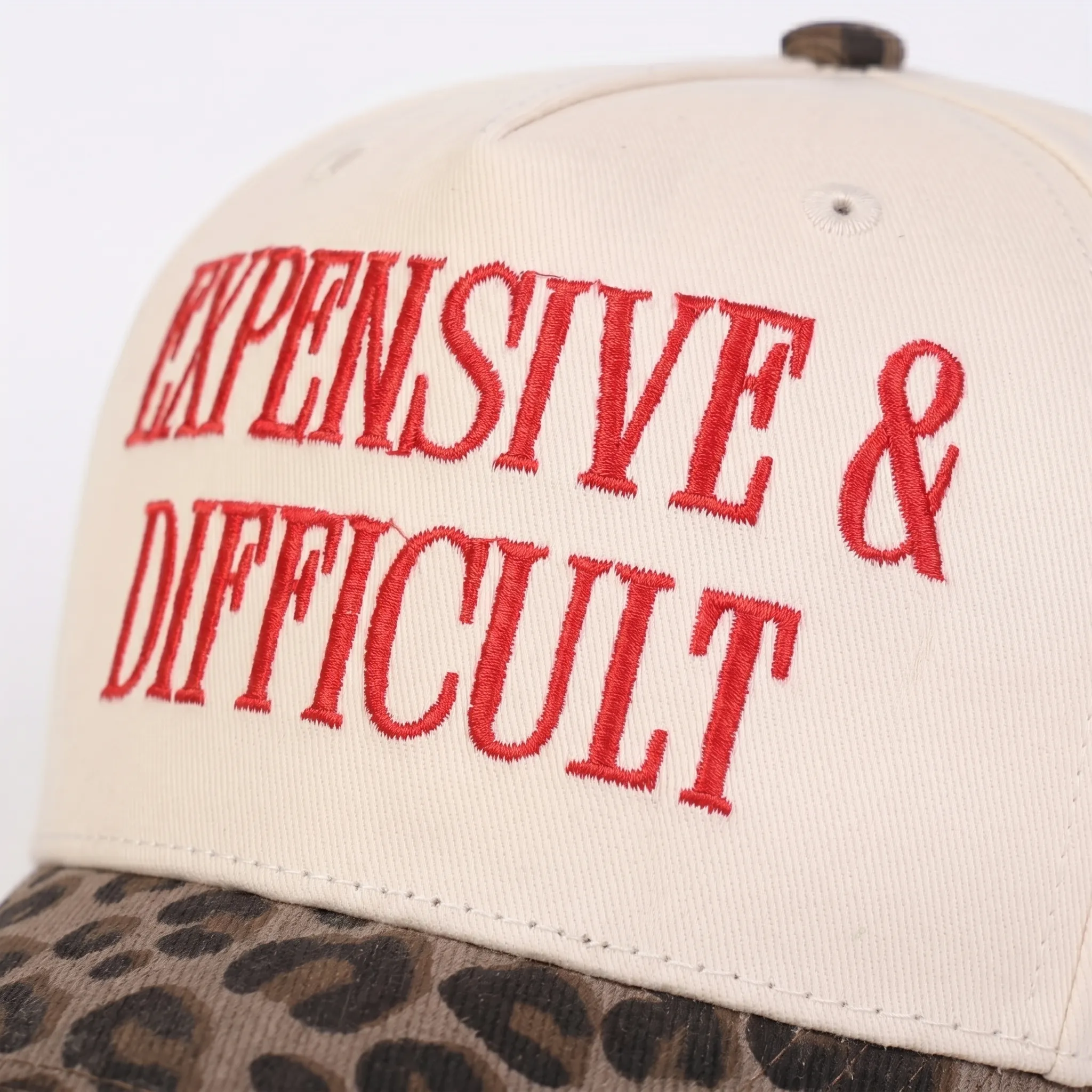 Close-up of red embroidery on cream cotton baseball cap with leopard brim